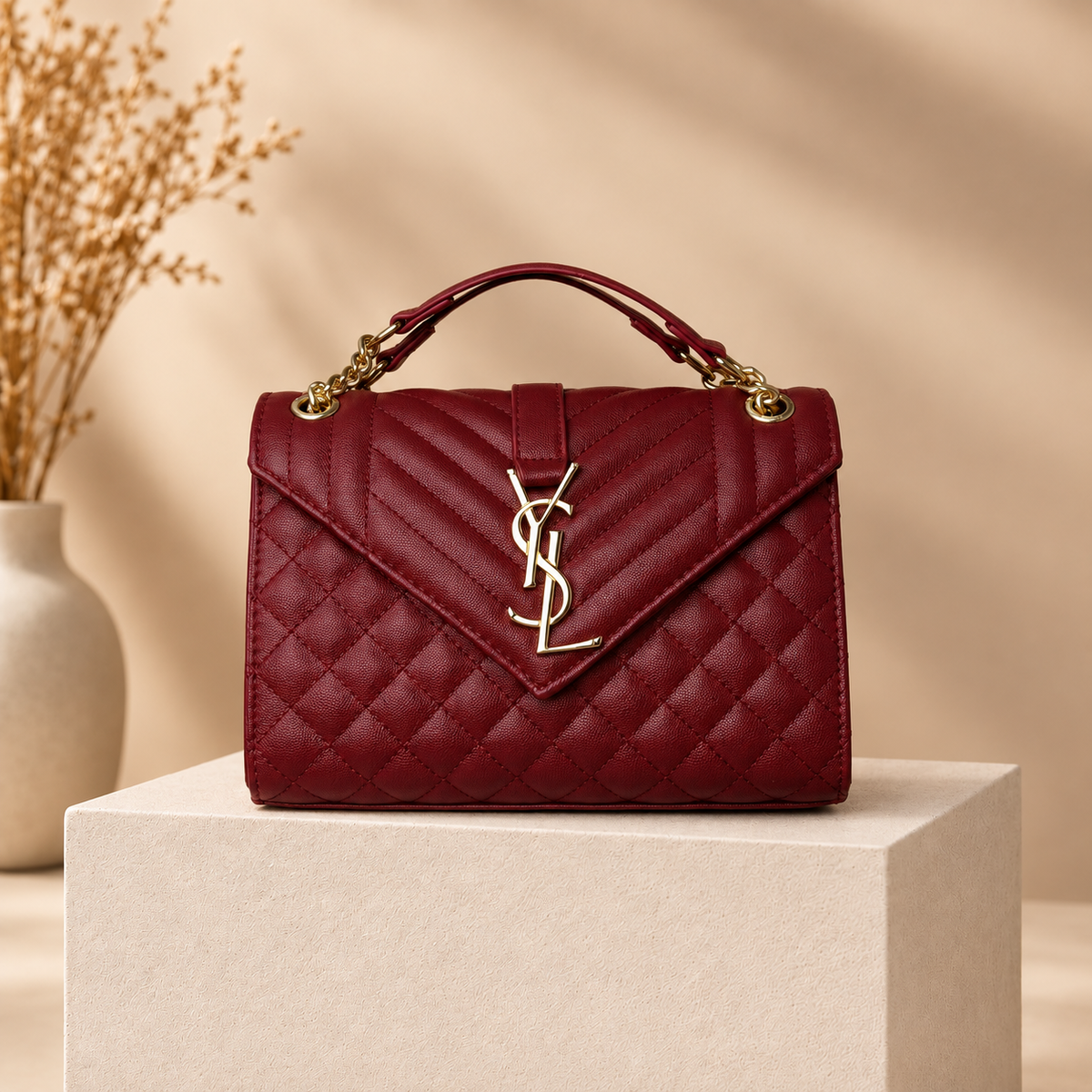 B02 burgundy quilted handbag on warm beige studio pedestal